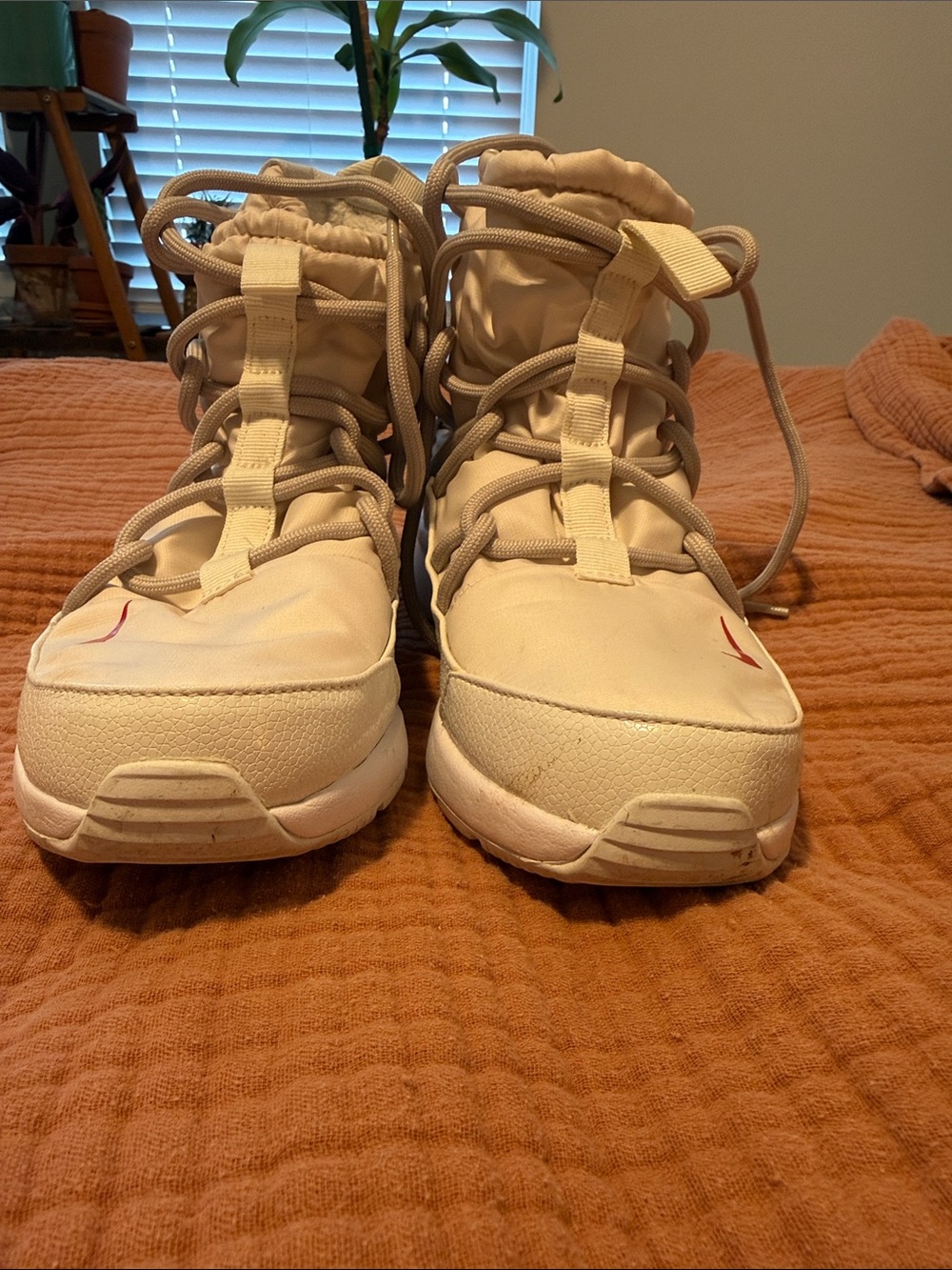 Nike high top sneaker boots in a cream/off white color with red Swoosh accents.